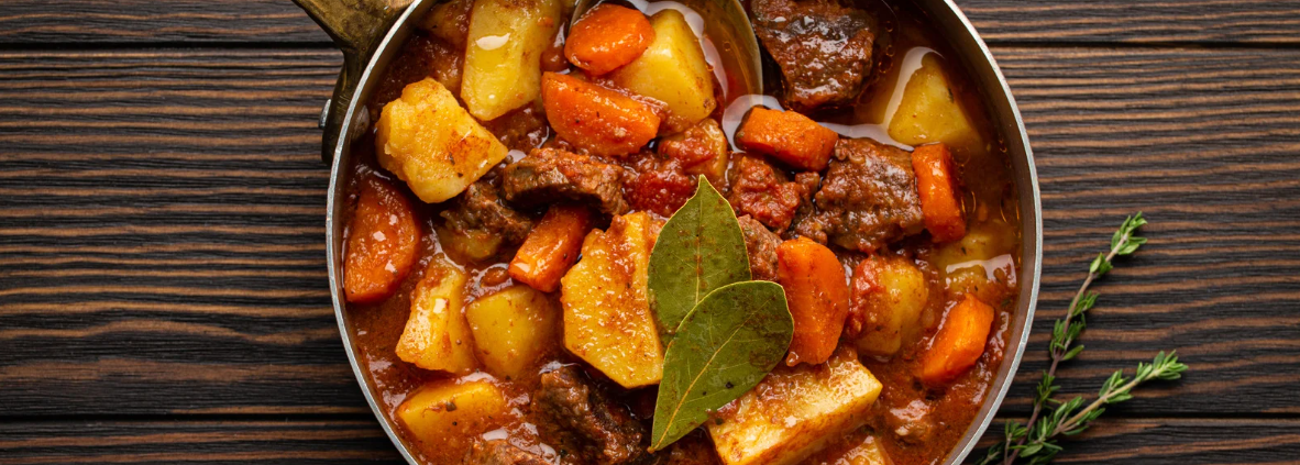 Sartén con calderete de cordero, con trozos de carne tierna, patatas, zanahorias, pimientos y cebolla, todo en su caldo sabroso. Un guiso tradicional preparado en sartén.