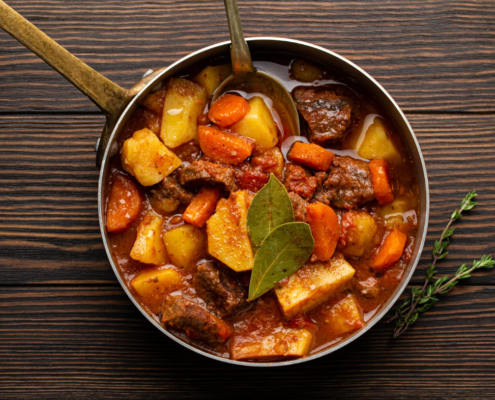 Sartén con calderete de cordero, con trozos de carne tierna, patatas, zanahorias, pimientos y cebolla, todo en su caldo sabroso. Un guiso tradicional preparado en sartén.